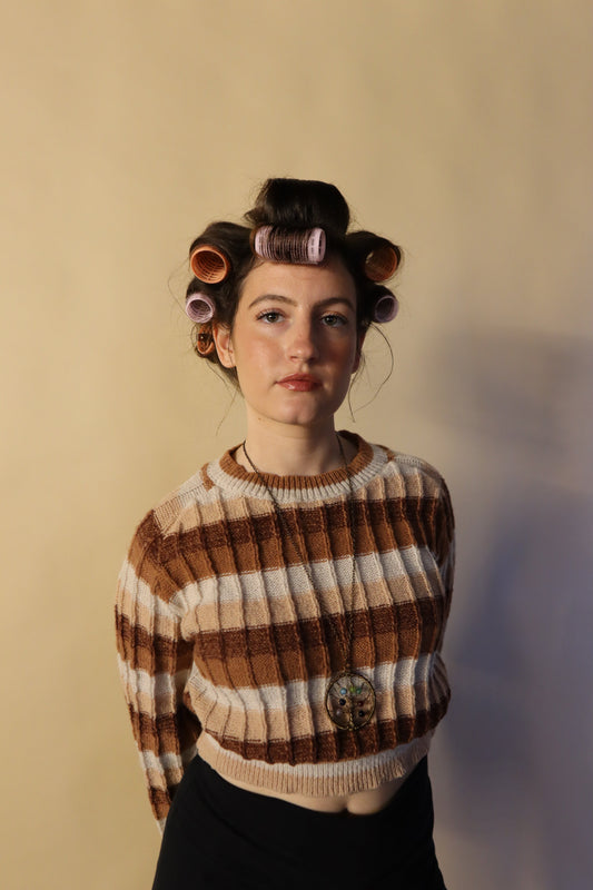 Woman wearing a striped sweater with hair rollers in her hair, preparing for a curly hair routine — representing Blush+Bounce’s simple approach to healthy, hydrated curls